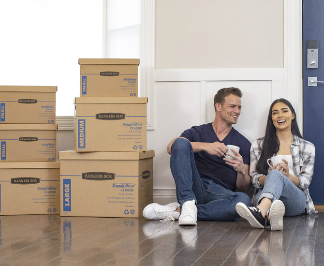 Man and woman sitting on floor next to stacked boxes