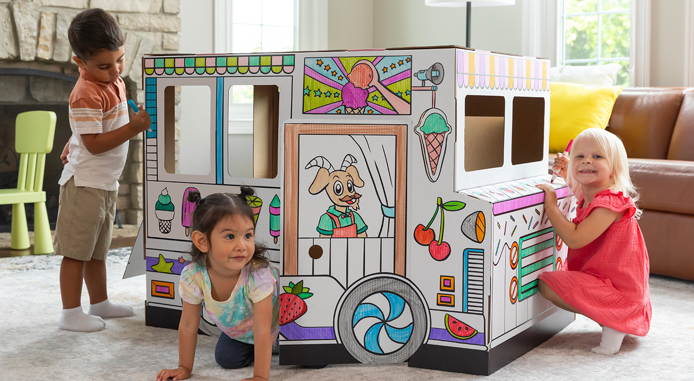 Image of a boy and two girls playing in and around an At Play Cardboard Vehicle