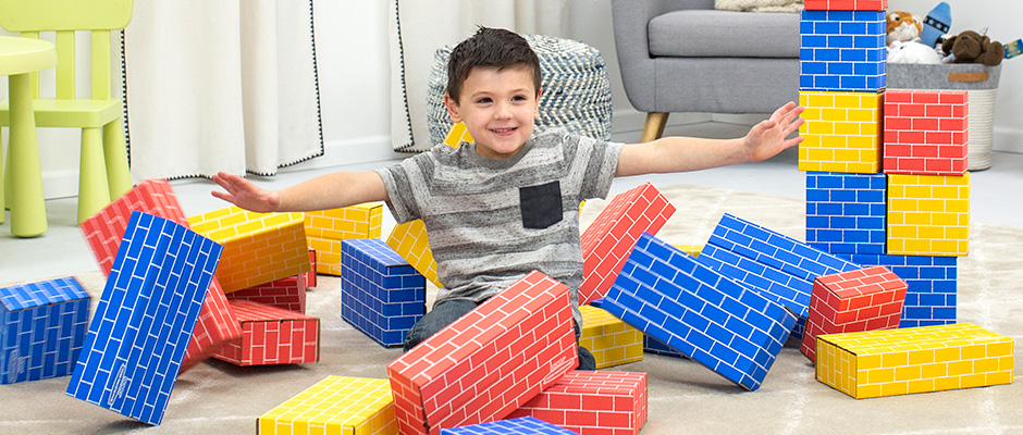 Image of a young boy knocking over a bunch of Bankers Box At Play blocks