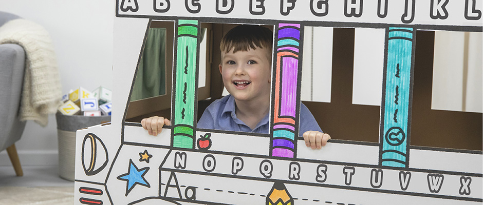 Image of a young boy playing in a Bankers Box At Play Cardboard Vehicle