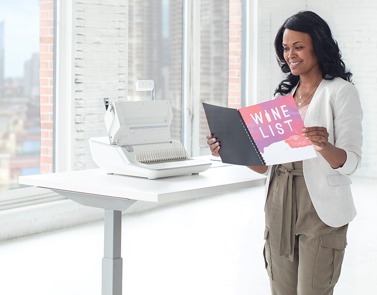 Woman sitting at desk looking off-screen while next to a shredder