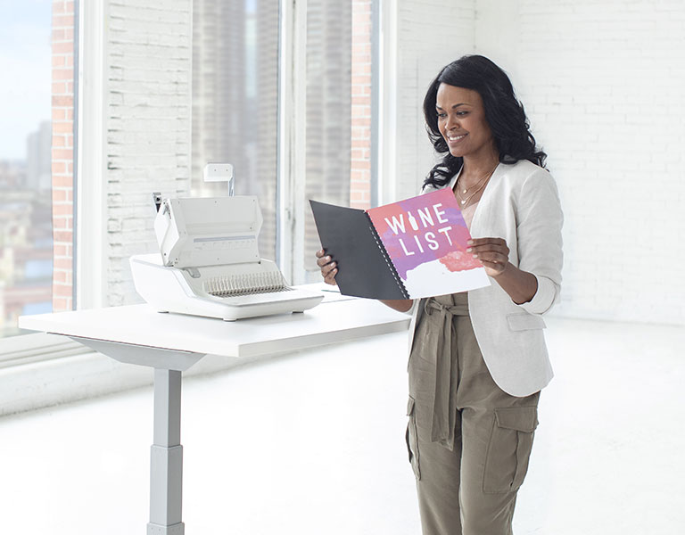 Woman sitting at desk looking off-screen while next to a shredder