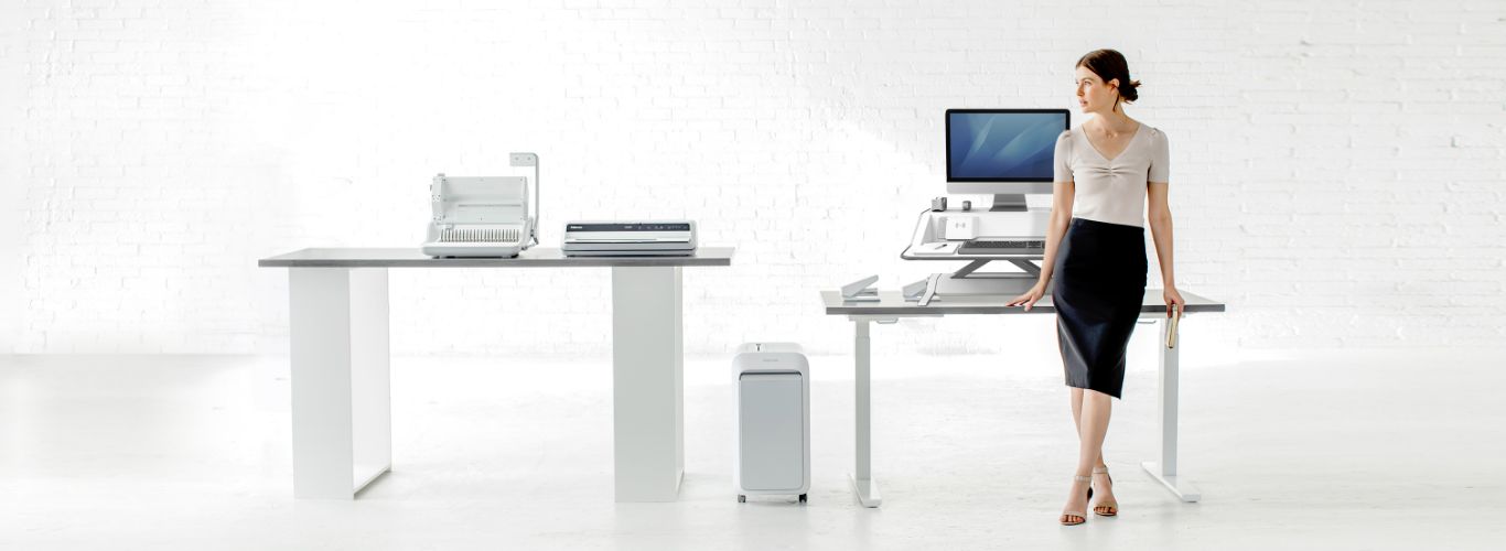 Woman sitting at desk looking off-screen while next to a shredder