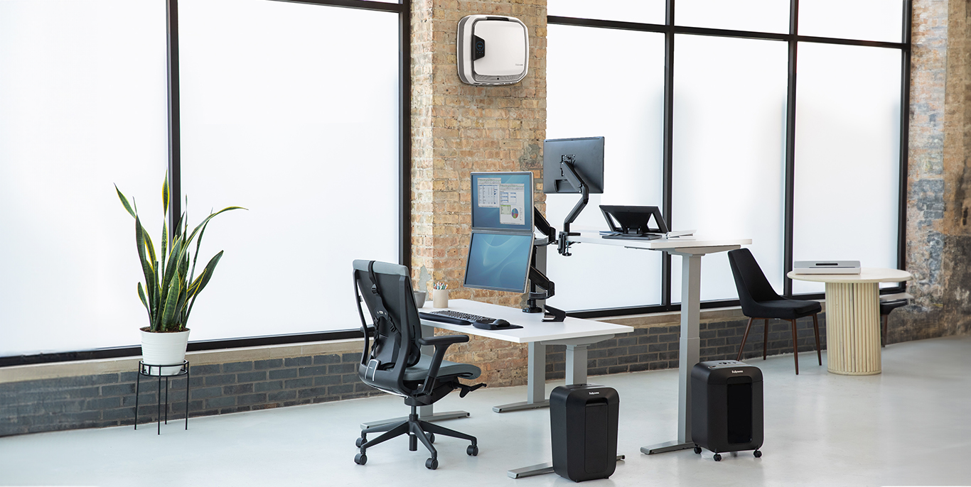 man seated at desk working, woman on the opposite side of him standing at her standing desk also working