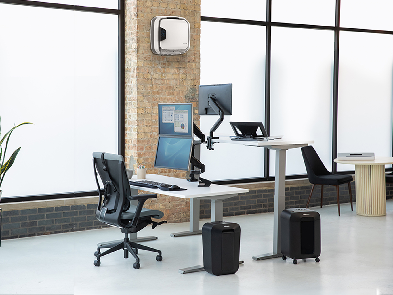 man seated at desk working, woman on the opposite side of him standing at her standing desk also working