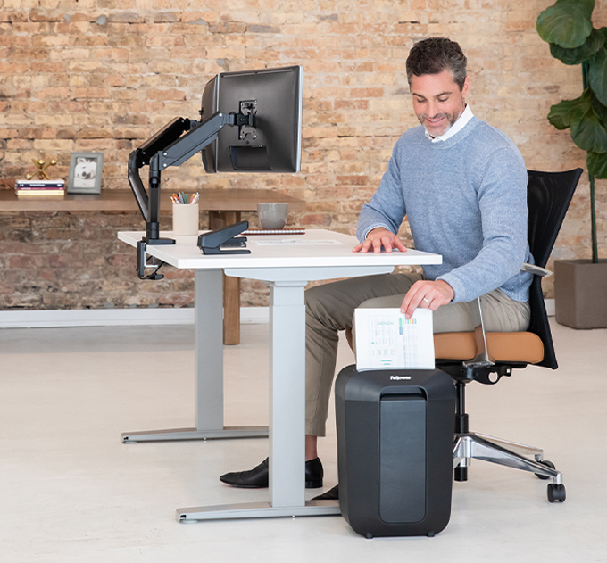 Man sitting at desk, shredding some papers