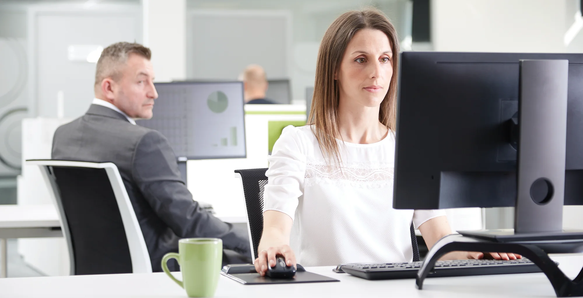 Man looking over the shoulder at a woman who is working's screen