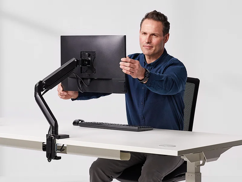 Man adjusting a monitor on an arm