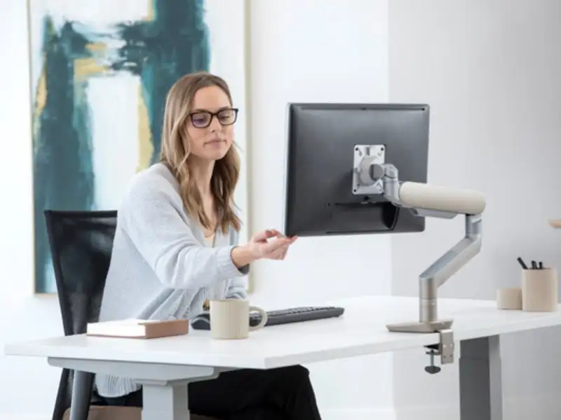 woman adjusting a monitor arm