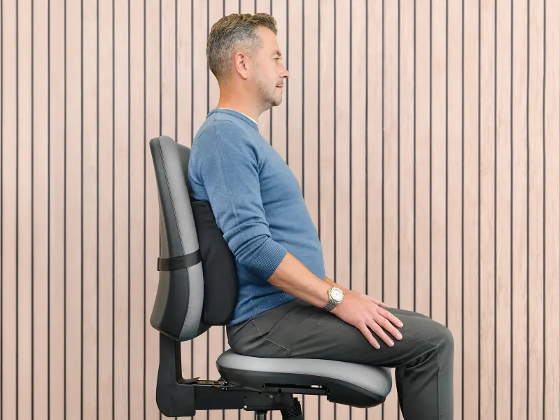 Man sat upright in a chair with a lumbar support
