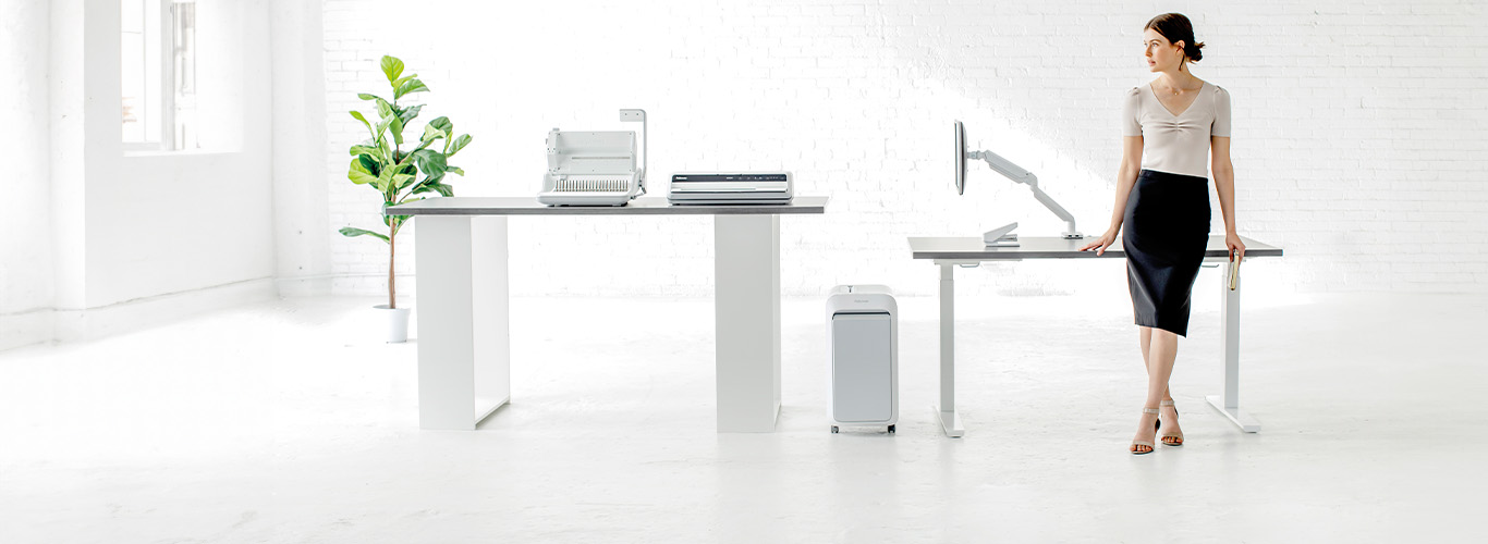 Woman sitting at desk looking off-screen while next to a shredder