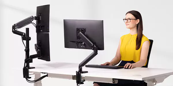 A lady sat at a desk looking at monitors
