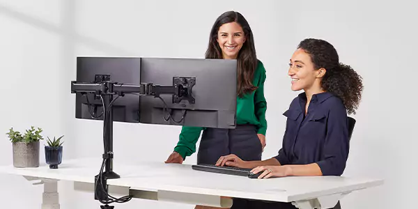 Two female colleagues talking behind a monitor