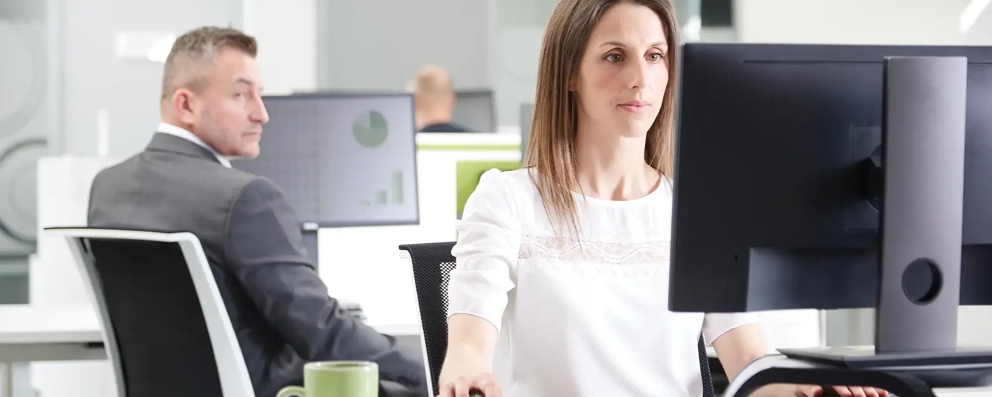 Man looking over the shoulder at a woman who is working's screen