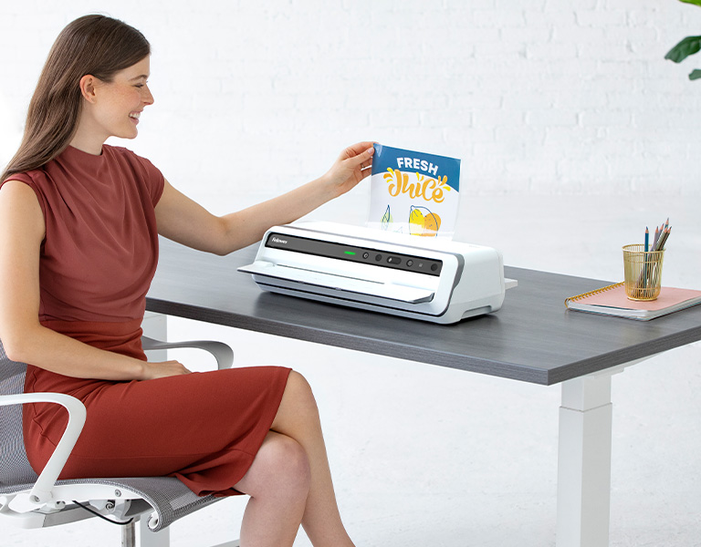 Woman sitting at desk next to a laminator