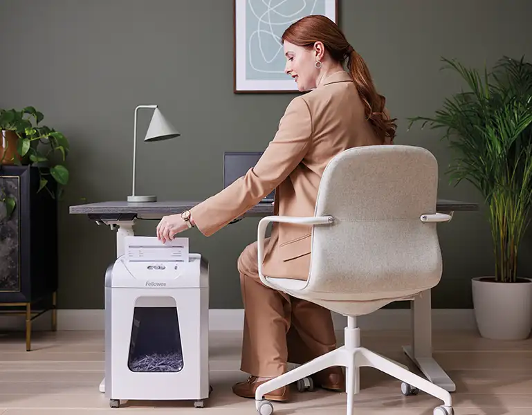 woman at a desk using a Fellowes shredder