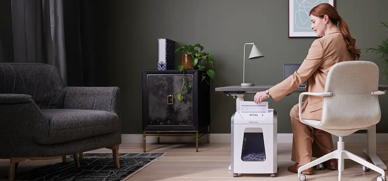 woman at a desk using a Fellowes shredder