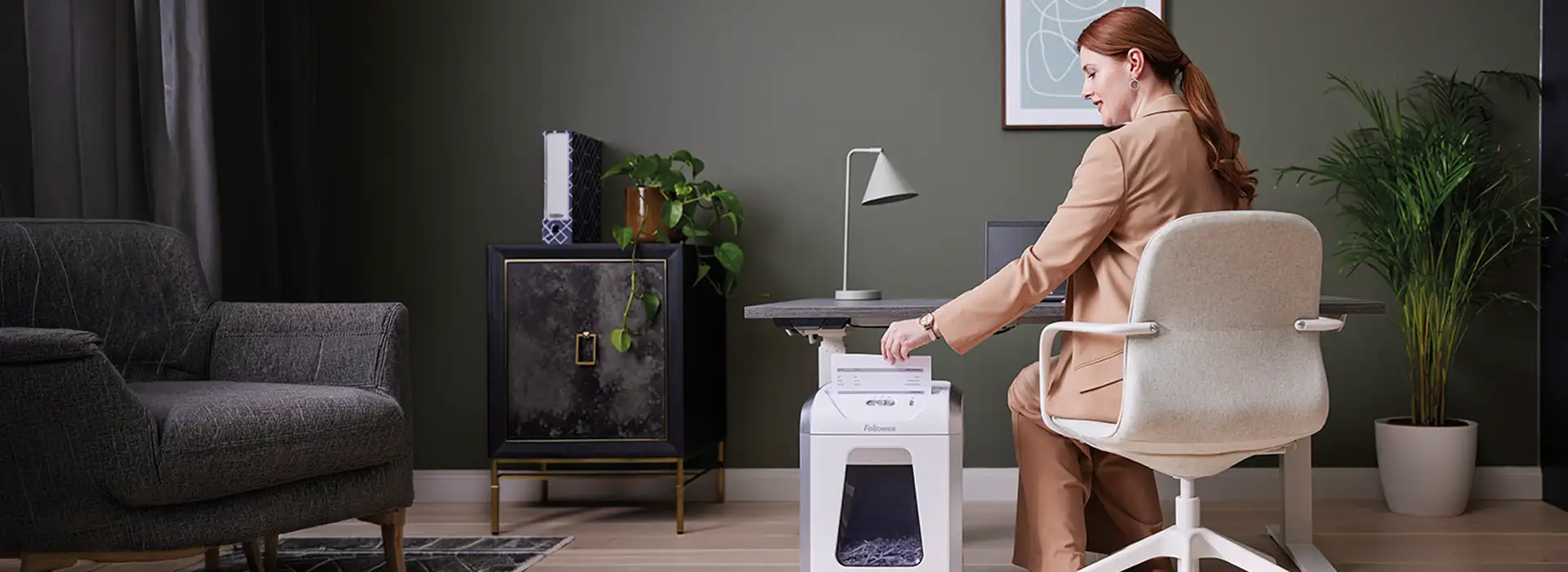 woman at a desk using a Fellowes shredder