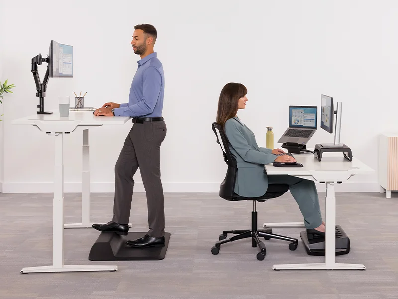 Man and woman using sit-stand desks both standing and seated