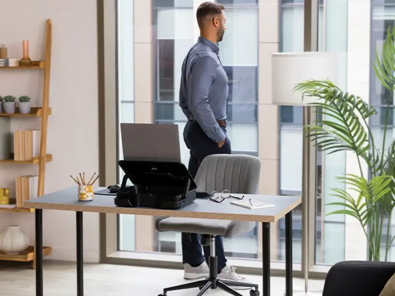 Man looking out of a window next to a desk