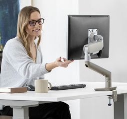 Image at woman adjusting her monitor at her desk