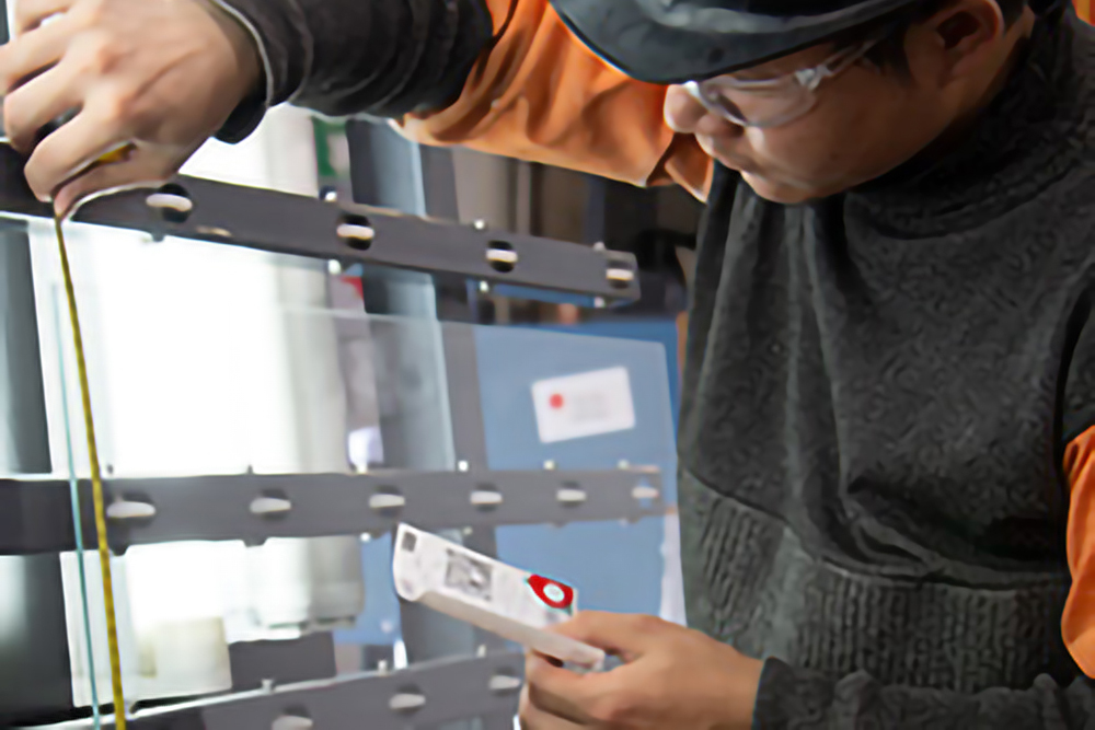 Image of a man in a hard hat measuring the glass of a markerboard