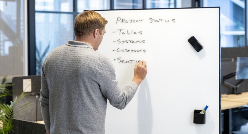 a man writing the project status list on an eM Markerboard