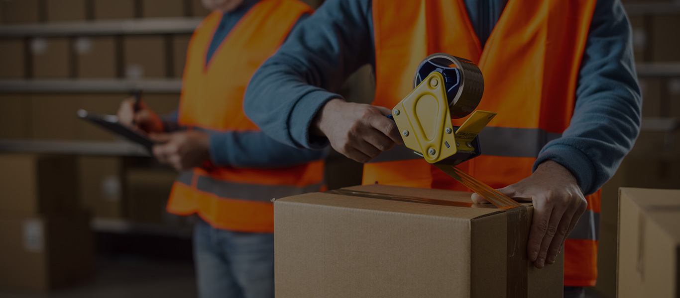 Image of a man taping up a box in a warehouse