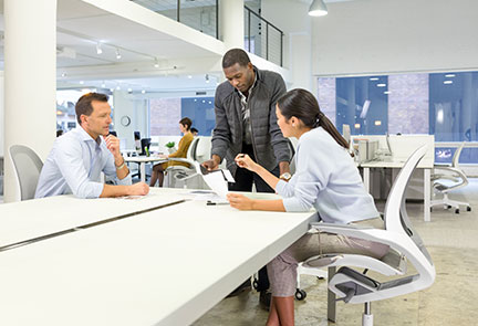 Two men and a woman conversing at desk