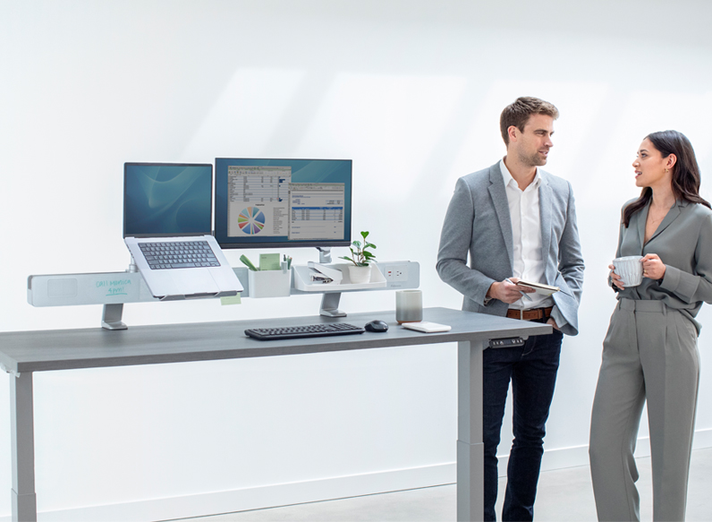 Man at table showing a woman how to use the laminator