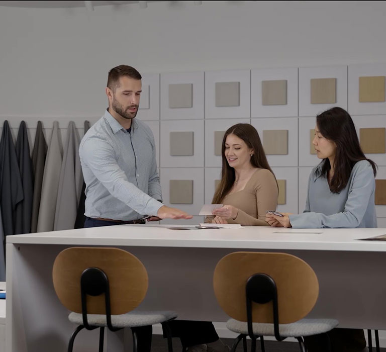 Still shot of people discussing fabrics at a desk