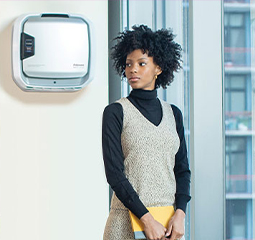Imagem de uma mulher de pé em frente a um purificador de ar