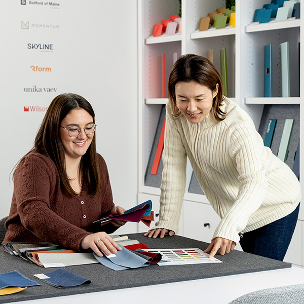 two women discussing paint swatches in an office area