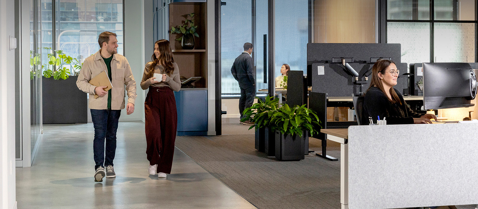 Image of two people walking down a hallway talking casually in an office building